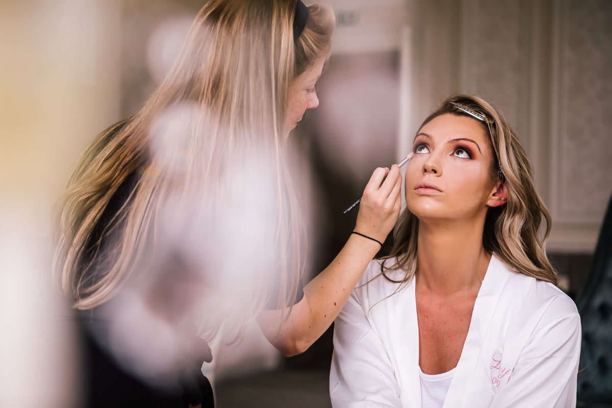 Makeup artist applying makeup to bride